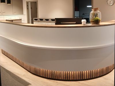 Der geschwungene weiße Tresen der Anmeldung mit Holzlamellen und Lichtband