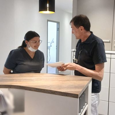 Eine Mitarbeiterin und Zahnarzt Raimund Hegge besprechen sich an der Anmeldung